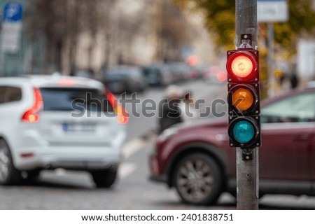a city crossing with a semaphore on blurred background with cars in the evening streets, red light