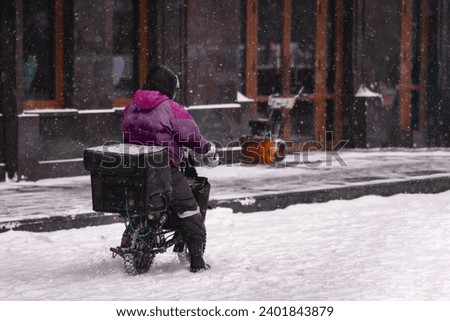 A delivery man on an electric motorcycle rides in the snow