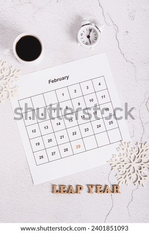 Leap year concept, calendar, coffee, alarm clock and text on light top and vertical view Royalty-Free Stock Photo #2401851093