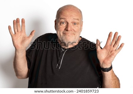Confident 58-Year-Old White Male Portrait on White Background with Raised Hands in Black Shirt - Stock Photo