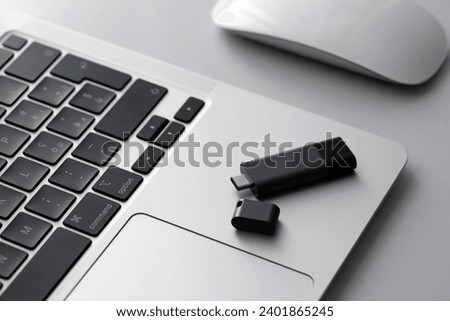USB flash drive lying on grey laptop case in front of his keyboard. Virtual memory storage with USB type-c output