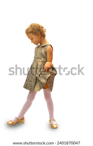 Girl on a white background looks down, holds her dress with her hand, putting her leg forward