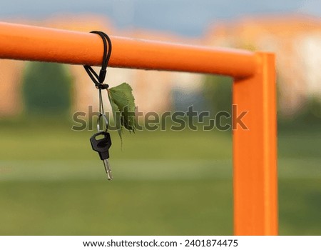 Lost car or home keys to hang on metallic orange tube in outdoors . It is clearly visible place for lost objects . Copy space.