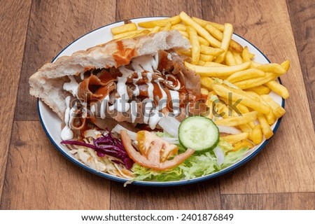 Doner Kebabs on plates, in pitta bread, with salad, with chips, munchy boxes, doner wrap  Royalty-Free Stock Photo #2401876849