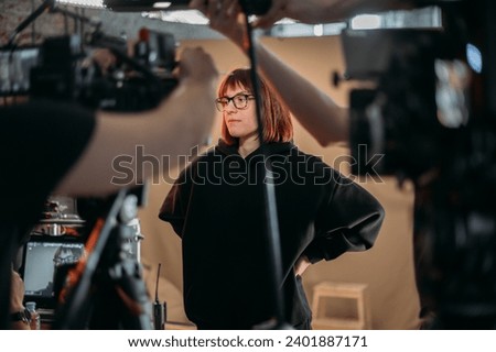 The director is a woman at work on the set. The director works with a group or with playback during the filming of a movie, commercial or TV series. Film crew, equipment and group. 