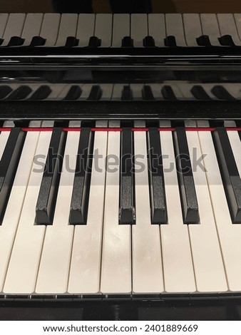 front view of a piano keyboard with its reflection on the lid, full musical octave, musical scale, piano keys, vertical Royalty-Free Stock Photo #2401889669