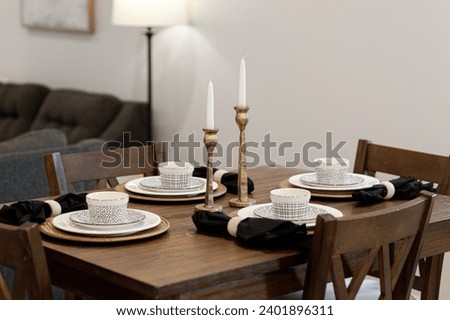 Farmhouse Modern Dining Room Table Set with Patterned Ceramic Plates, Black Napkins, and Brass Candlesticks for a Cozy Evening Dinner