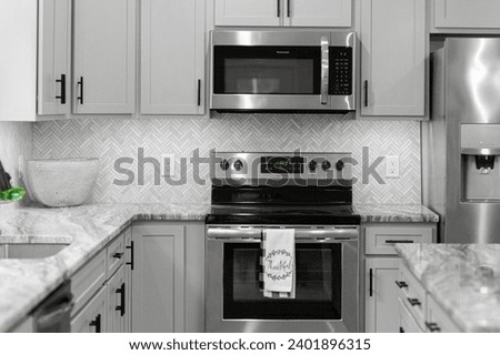 Clean Modern Kitchen Design with Stainless Steel Appliances and Herringbone Tile Backsplash Complemented by Grey Cabinets Royalty-Free Stock Photo #2401896315
