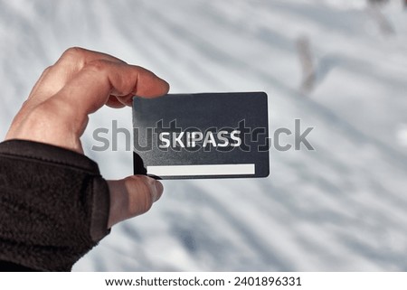 Ski pass held in hand by skier in a snowy mountain landscape