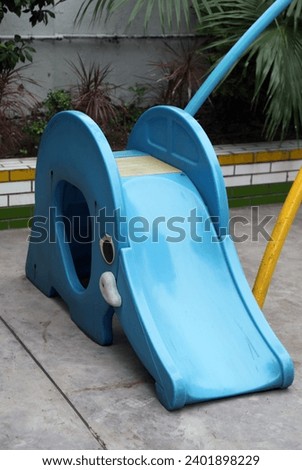 Exterior photo view of a plastic toy slide toboggan sled in an elephant design shape for kids child children to play and have fun at the playground of the kindergarten or public park in court yard