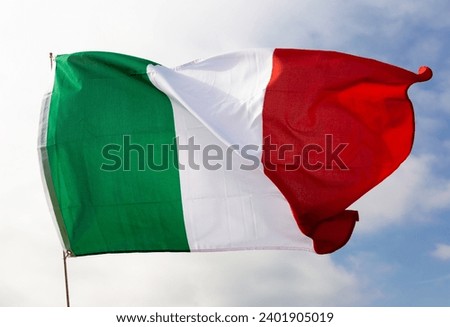 Large flag of Italy waving against background of sky and clouds