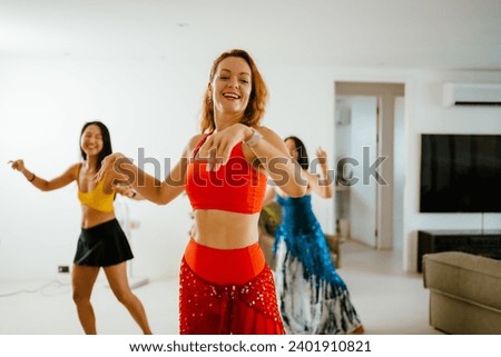 Picture of a group of female friends  performing Belly Dance in beautiful costumes. with fun at their homes, woman dance, Belly dancer in legging and hip scarf dancing, party celebration Royalty-Free Stock Photo #2401910821