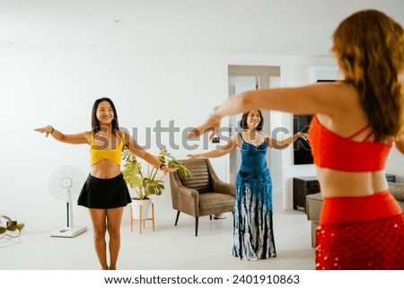 Picture of a group of female friends  performing Belly Dance in beautiful costumes. with fun at their homes, woman dance, Belly dancer in legging and hip scarf dancing, party celebration Royalty-Free Stock Photo #2401910863