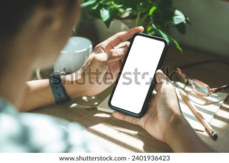 Close up view of man hands holding smart phone over working desk. Blank screen for your advertise design.