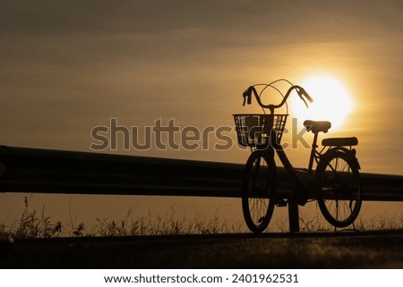 Bicycle on road concept, bicycle on sunrise sky background, big sun and sunny on golden blurred sky background