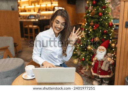 Young woman sitting in the restaurant and having a video call on laptop. Female professionals video calling on laptop sitting at cafe.