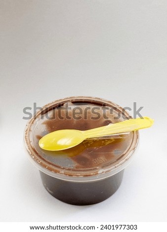 Top view photo of a small chocolate cake in a container with yellow spoon