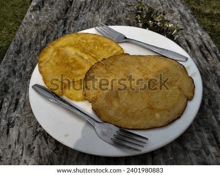 Two portions of plain pancakes on one plate, with two forks, on a plate served on a wooden table