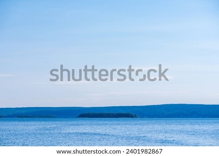 Beautiful water landscape with blue sky and forest on the horizon. Natural desktop background.