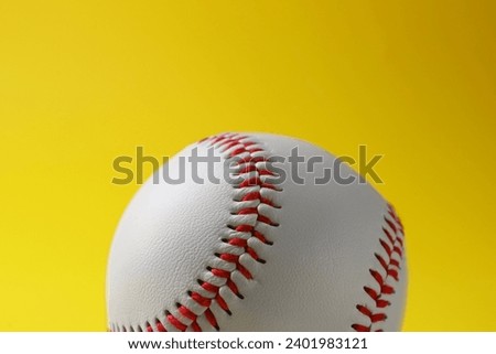 One baseball ball on yellow background, closeup
