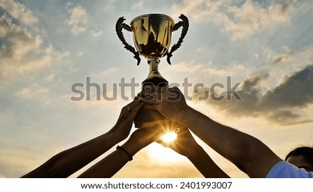 Success of teamwork, joint achievement of goal in business and life. Winning team is holding trophy in hands. Silhouettes of many hands in sunset. Royalty-Free Stock Photo #2401993007