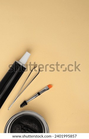 Flat lay composition with eyebrow henna and tools on beige background. Space for text