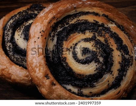 Two delicious buns with poppy seeds lie on a wooden background.