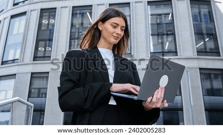 Banner. Panoramic photo. A young woman with a laptop on the background of office buildings. Focused work