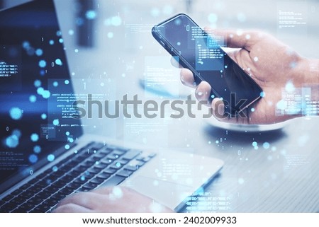 Close up of hands using laptop and cellphone with creative binary coding hologram on blurry background. Software programming code. Double exposure