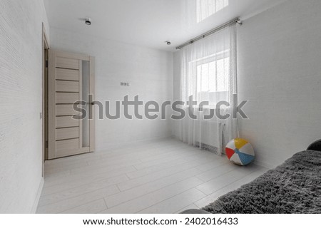 Space of empty white children's room with sofa and colorful inflatable ball.
