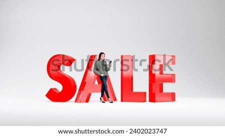 Cheerful young European woman with smartphone standing near big sale sign over white background. Concept of discount and holiday season
