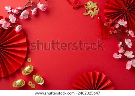 Top view of jubilant setting featuring fans, Feng Shui symbols, auspicious coins, sycee, wall art with a dragon motif, and orchids against a red background, frame for your text or advertising Royalty-Free Stock Photo #2402025647