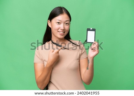Young Asian woman with ID card over isolated background and pointing it