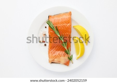 Fresh salmon fillet close up on plate decorated with sprig of fresh rosemary, sweet peas, slice of lemon isolated on white background. Useful healthy eating concept. Vitamins, proteins, Omega3