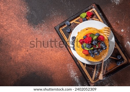 Healthy summer morning breakfast pancakes with fresh berry. Stack of traditional pancakes with blueberry, raspberries, honey. Healthy morning breakfast on dark background