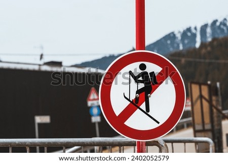 A no ski climbing sign prominently displayed against a backdrop of distant mountains and a metal barrier. Amidst nature’s beauty lies danger heed the warning signs to ensure a safe experience.