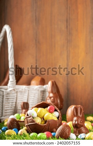 Easter egg hunting background. Various candy and chocolate Easter eggs, bunny and rabbits with basket for eggs on green grass park or garden background