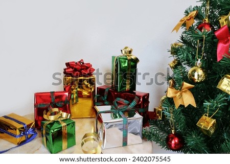 Assorted color gift boxes and an artificial Christmas tree decorated with balls. Ribbons for Christmas and special occasions cream background

