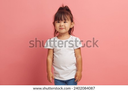 Handsome three years old little asian girl wearing in white shirt standing on a pink isolated.  Royalty-Free Stock Photo #2402084087