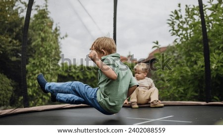 Little boys, brothers jumping on trampoline in the backyard, doing somersaults. Dangers and risks of trampoline for kids. Royalty-Free Stock Photo #2402088559