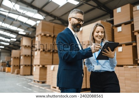 Female warehouse manager talking with logistics employee in warehouse, planning transport of products, goods, talking shipping process.