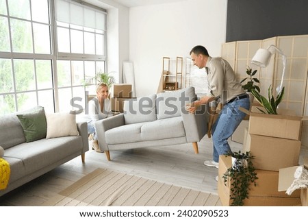 Mature couple carrying sofa in room on moving day Royalty-Free Stock Photo #2402090523