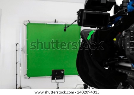 Setup in a TV studio with green screen, lights, and camera