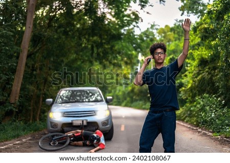 Calls for Immediate Assistance after Young Asian man driving a car crashes into a cyclist falls and injured, Cyclist in need of urgent aid, Unexpected Roadside Encounter, Outdoor Mishaps Royalty-Free Stock Photo #2402108067