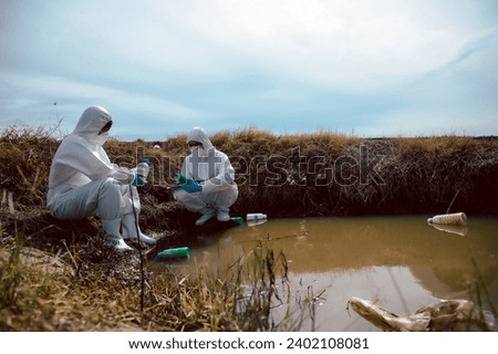 Team of scientists or biologists wears protective clothing to collect water samples from a natural water source with chemical-filled bottles of trash. Water pollution concept.