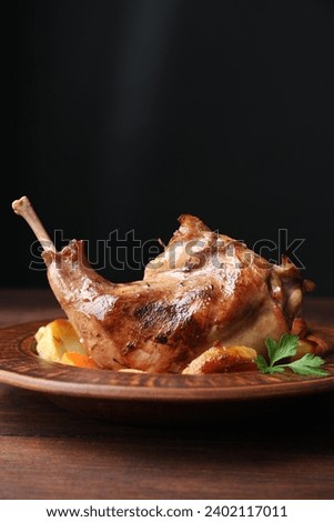 Tasty cooked rabbit meat with potatoes on wooden table