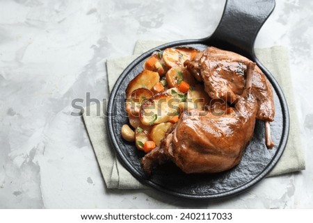 Tasty cooked rabbit meat with vegetables on light grey table, above view. Space for text