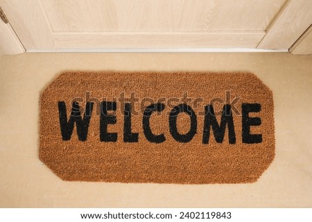 Doormat with word WELCOME in hall, top view Royalty-Free Stock Photo #2402119843