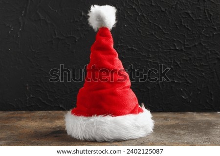 Santa Claus hat on table near black grunge wall