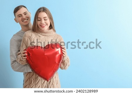 Lovely couple with heart-shaped balloon on blue background. Valentine's Day celebration Royalty-Free Stock Photo #2402128989